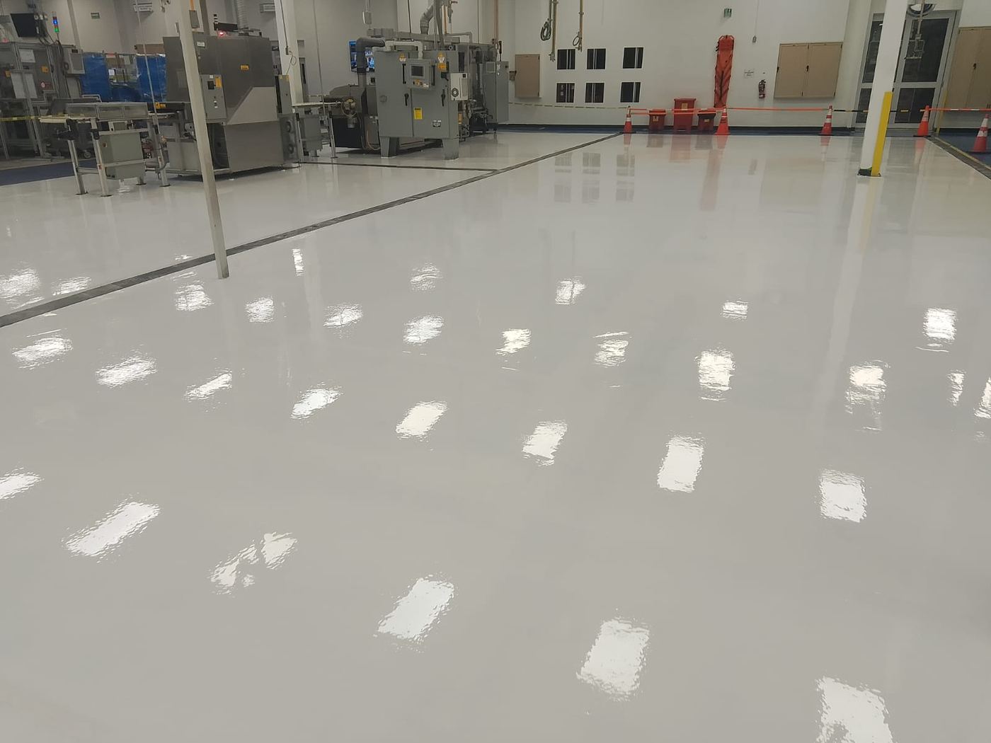 Piso epóxico gris brillante recién aplicado en nave industrial
